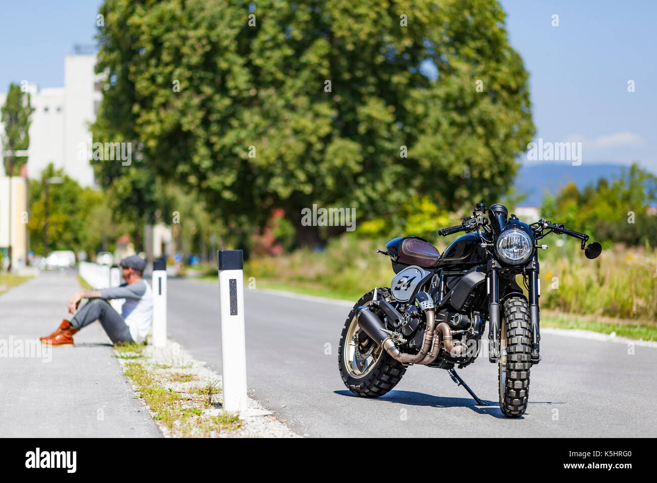 Cool aussehenden Motorrad Fahrer sitzen in der Nähe von custom made Scrambler Cafe Racer Stockfoto