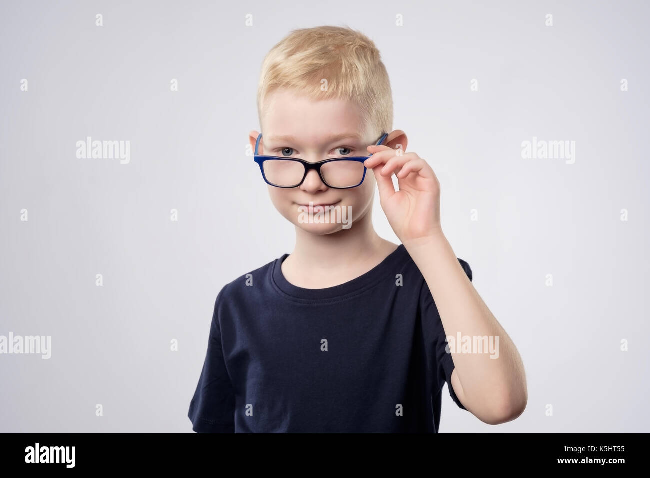 Cute kaukasischen blonde Junge mit Brille in der Nähe der Augen Stockfoto