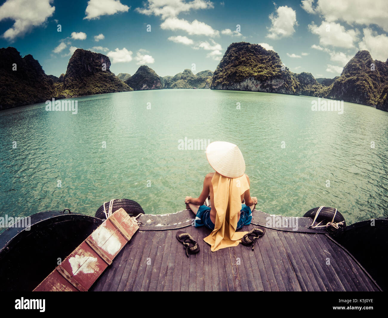 Mann mit einem vietnamesischen hat genießen die magnifiecent Anblick von Ha Long Bay Kalksteinfelsen an einem schönen sonnigen Tag während einer Bootsfahrt, UNESCO worl Stockfoto