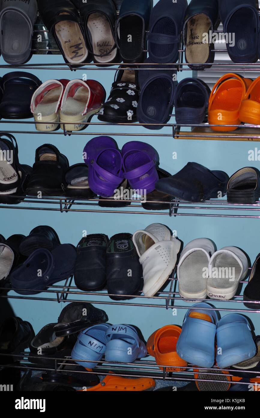 Clogs / Klinische Schuhe auf einem Schuhgestell in einer medizinischen Umkleidekabinen. VEREINIGTES KÖNIGREICH. Stockfoto