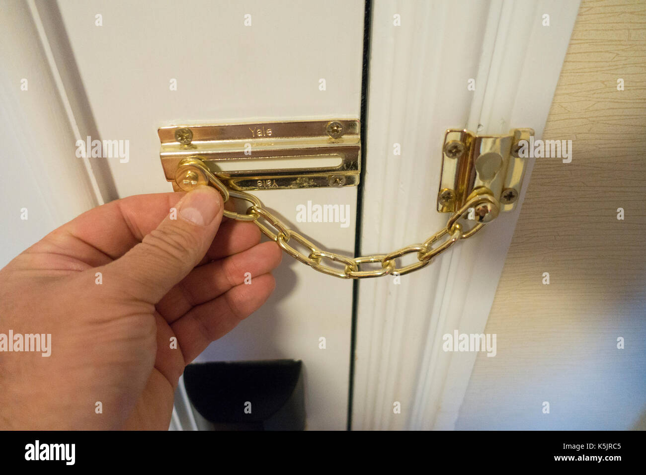 Personen, Hand, halten Sie ein Hotel oder eine Tür, auf der Innenseite der Kette Hotel Zimmer entweder zu entsperren oder sperren Tür für Sicherheit, England, Großbritannien Stockfoto