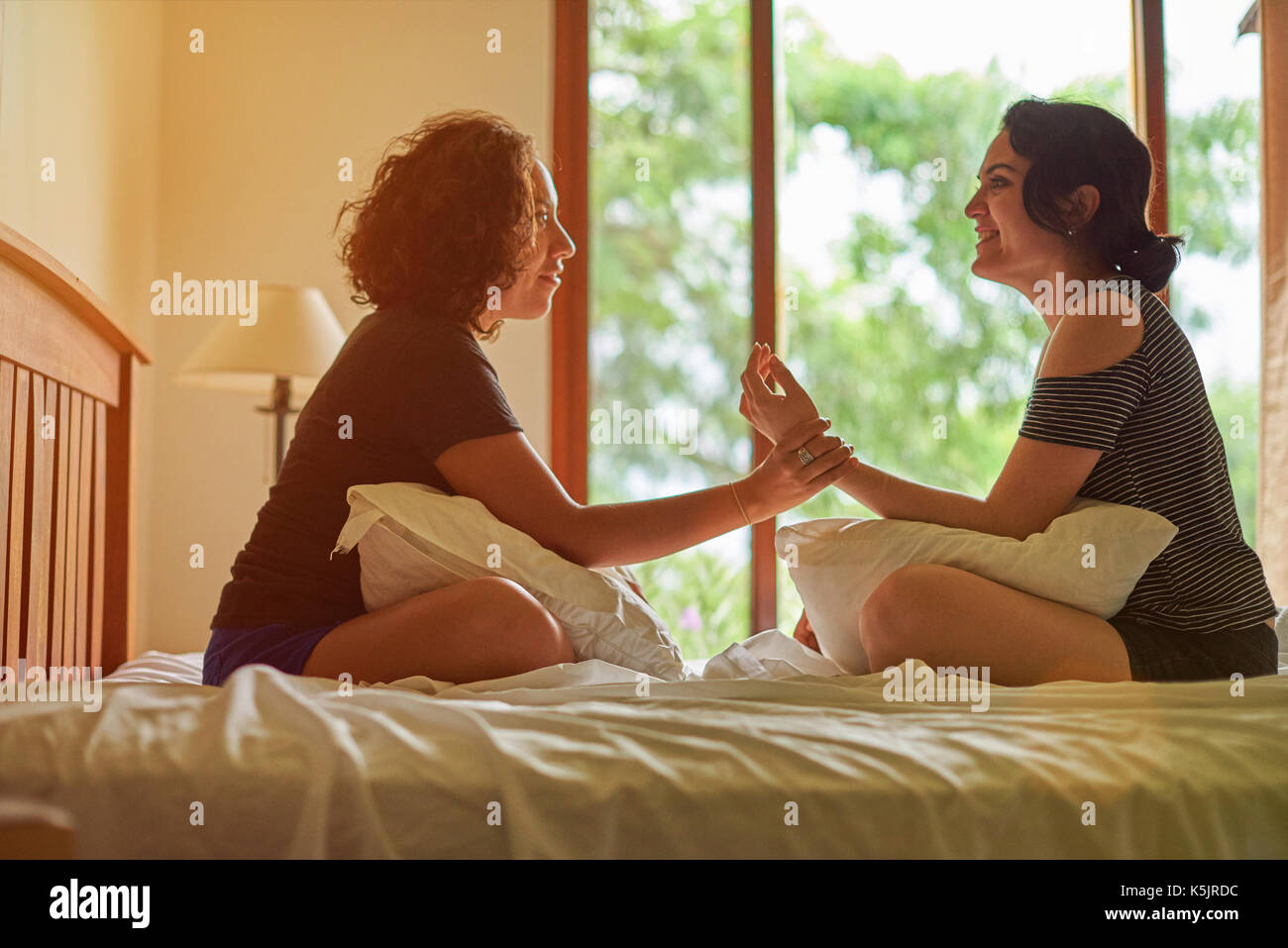 Zwei Hispanic Frau sprechen auf dem Bett in einem Raum mit großen Fenster Stockfoto