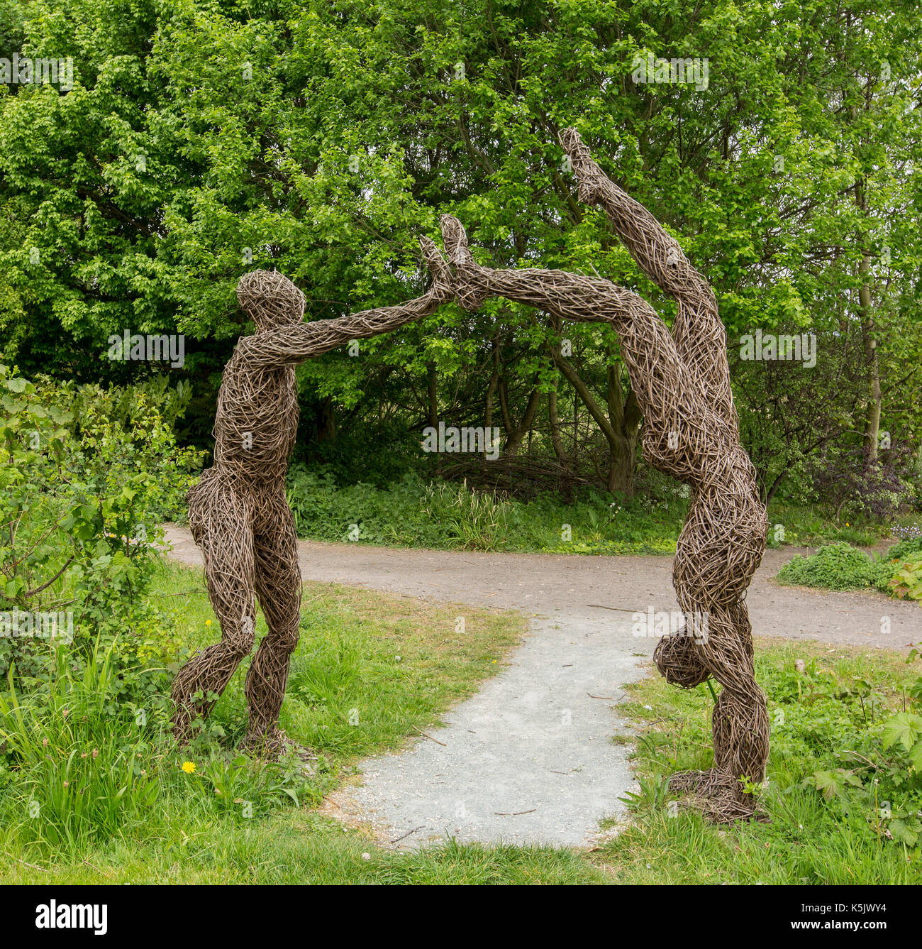 Ungewöhnliche Statuen, aus natürlichen Materialien, mit zwei Leben und Menschen sind, stellt man eine Hand stehen, bilden einen Torbogen über Weg in Englischer Garten Stockfoto