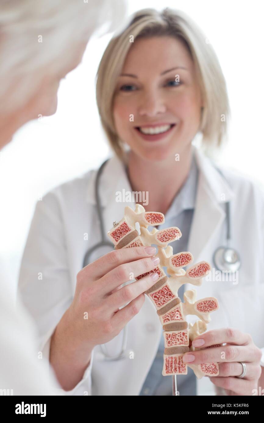 Weibliche Arzt zeigt Patienten ein anatomisches Modell der menschlichen Wirbelsäule. Stockfoto