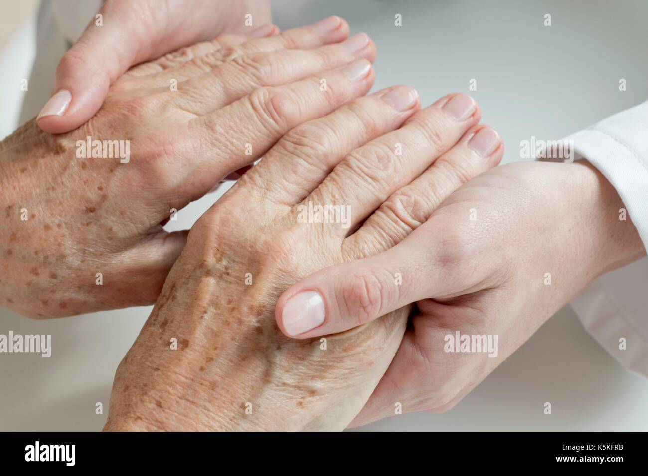 Ärztin untersuchen die Hände des älteren Patienten. Stockfoto