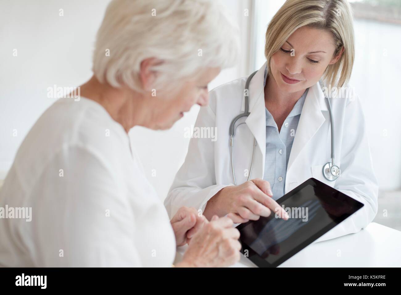Ärztin mit älteren Patienten röntgen von Hand auf digital Tablet. Stockfoto