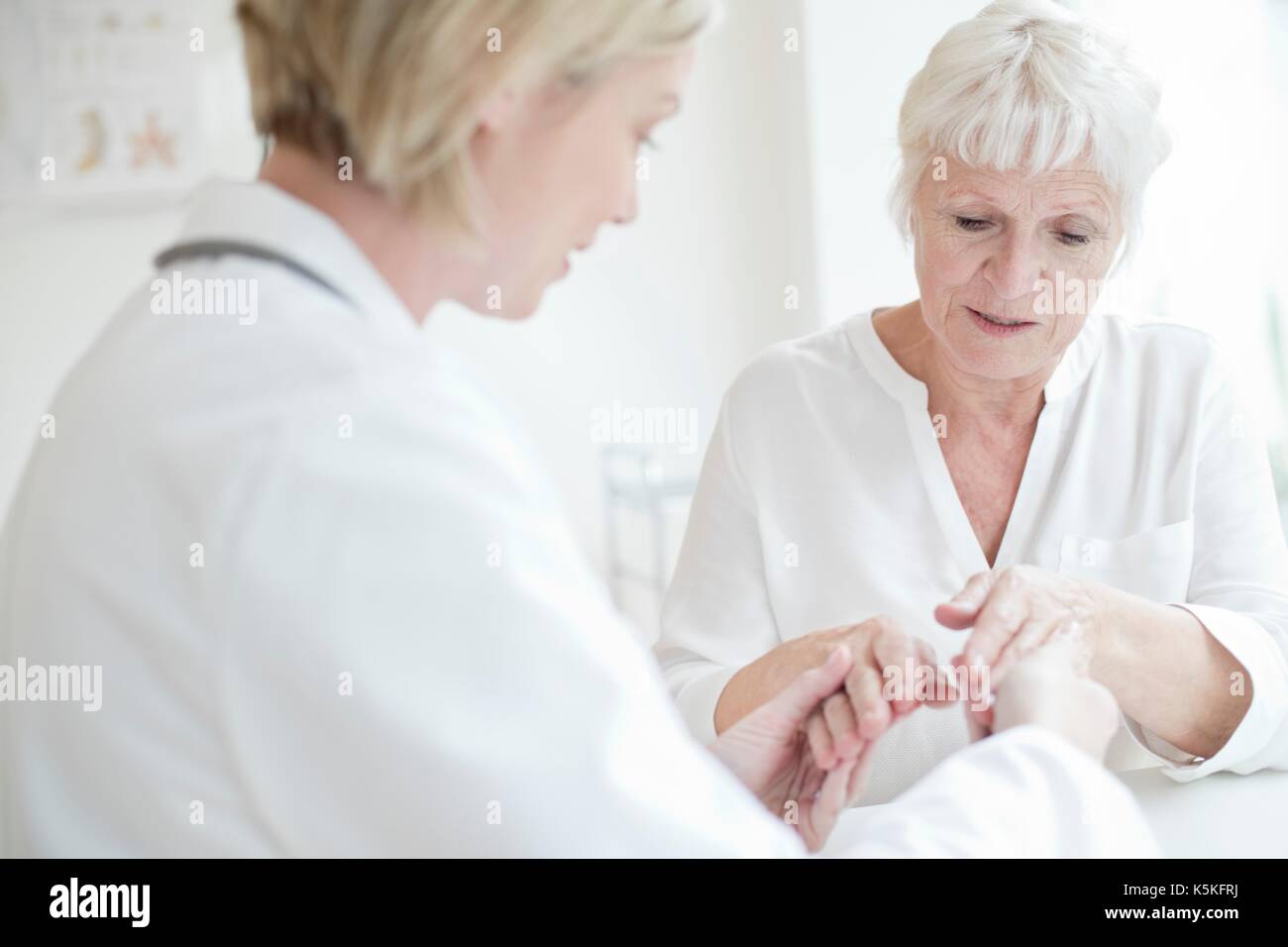 Ärztin untersuchen die Hand des älteren Patienten. Stockfoto