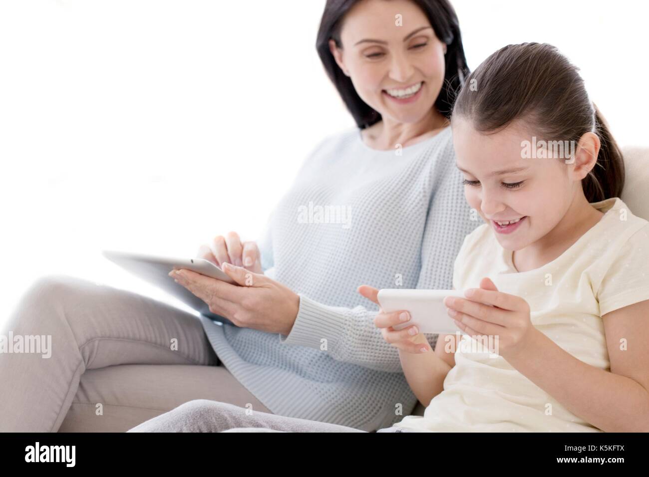 Mutter und Tochter auf Sofa mit digitalen Tablet-PC und Smartphone. Stockfoto