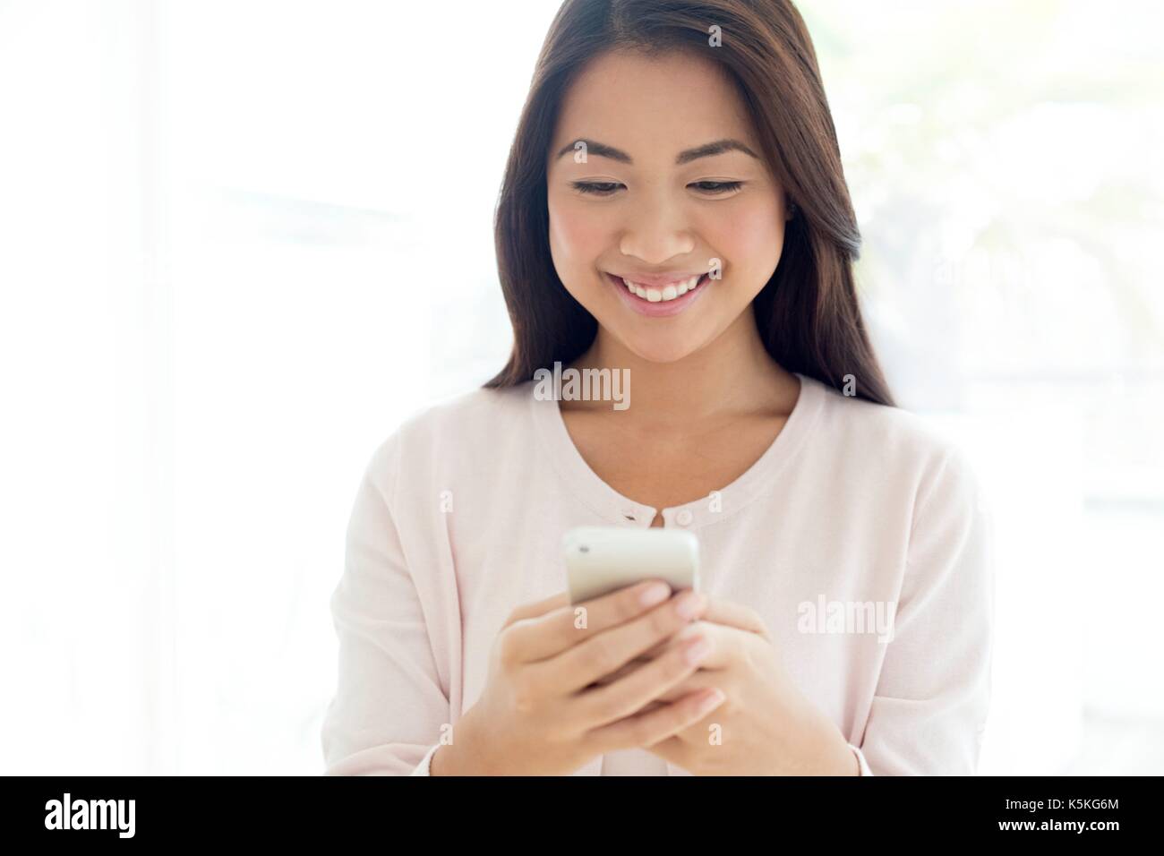 Junge Frau mit Smartphone, lächelnd. Stockfoto