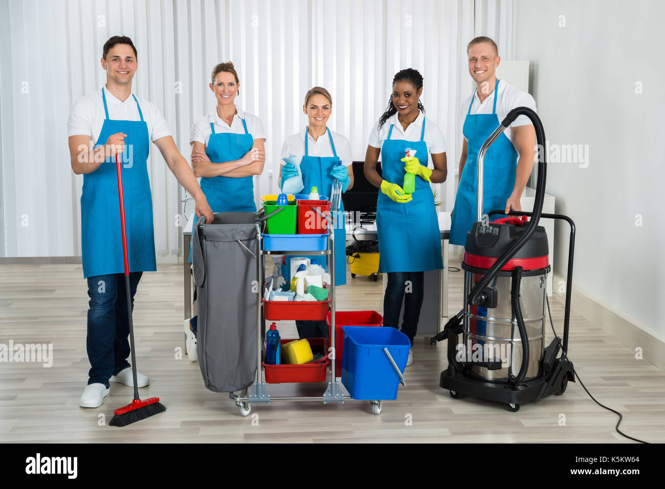 Gruppe von Happy Reiniger stehend mit der Reinigung der Geräte im Büro Stockfoto