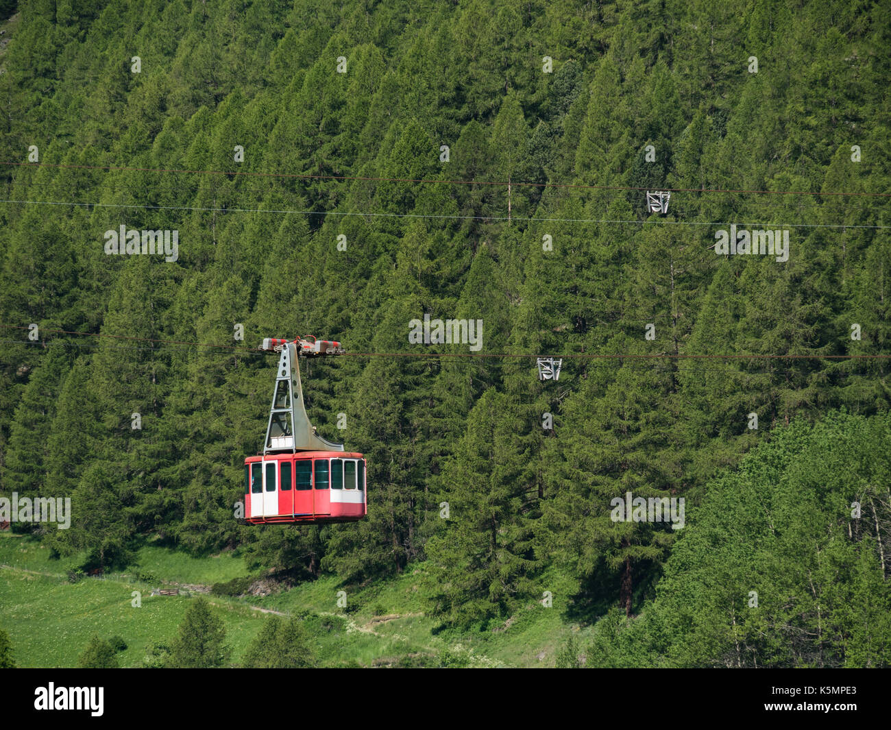 Seilbahn in den Schweizer Alpen, mit Pinienwald im Hintergrund, Zermatt, Schweiz. Stockfoto
