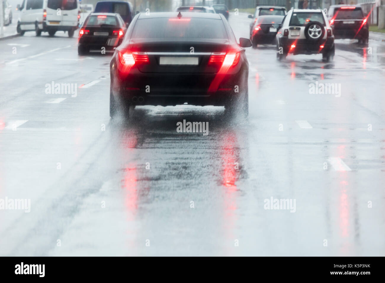 Verregnete Straße. Die Autos fahren auf nasser Straße mit Spritzwasser in Bewegungsunschärfe. Stockfoto