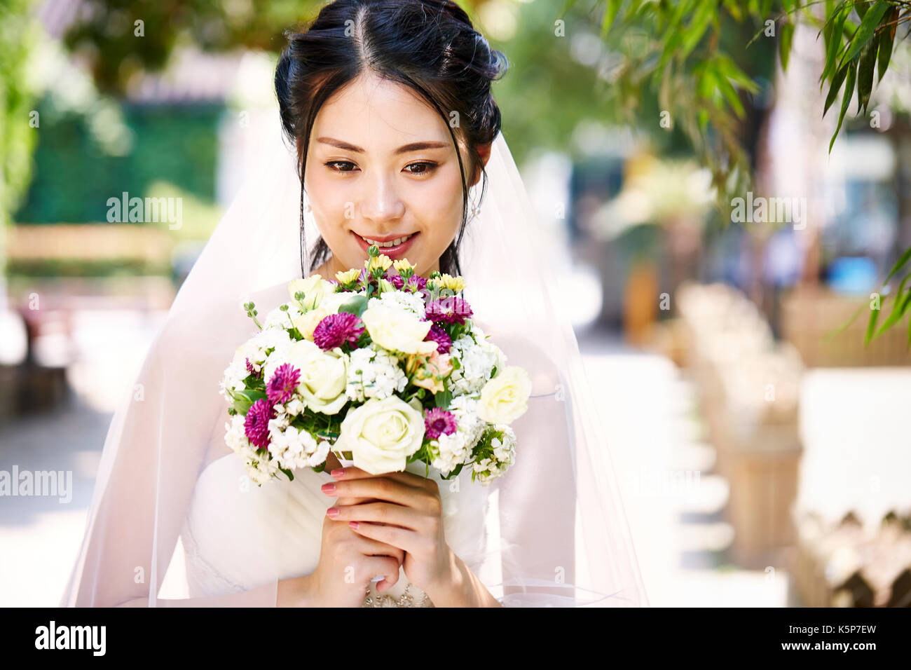 Schöne und glückliche junge asiatische Braut tragen Bridal Veil Holding ein Bündel von Blume Stockfoto