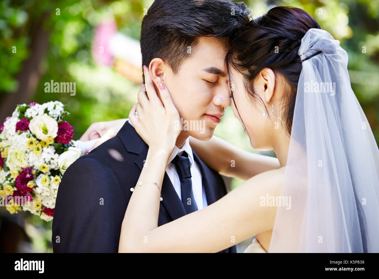 Junge asiatische Braut und Bräutigam küssen bei der Hochzeit Zeremonie Stockfoto