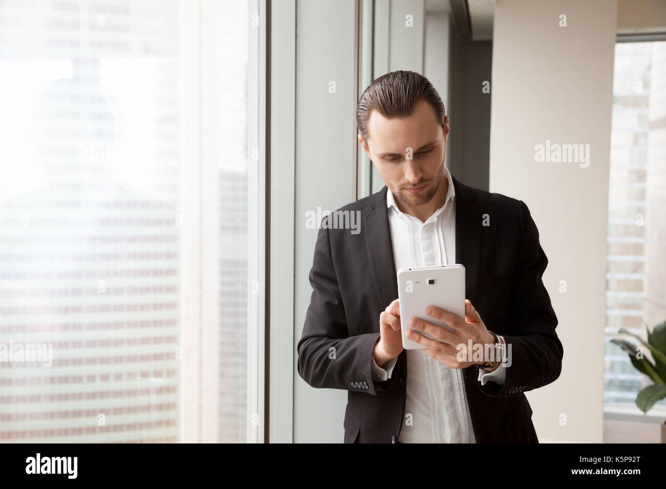 Junge Geschäftsmann im Anzug auf der Suche nach Informationen über elektronische Stockfoto