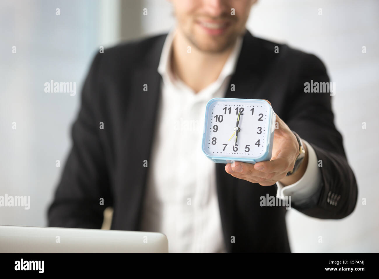 Lächelnd Geschäftsmann Holding kleine Uhr in der Hand. Stockfoto