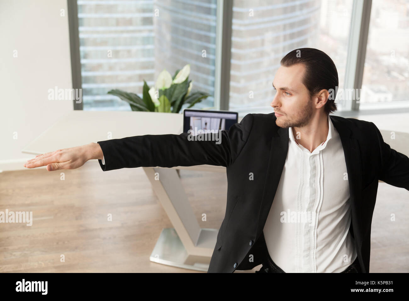 Junge Unternehmer Yoga am Arbeitsplatz im Krieger darstellen. Stockfoto