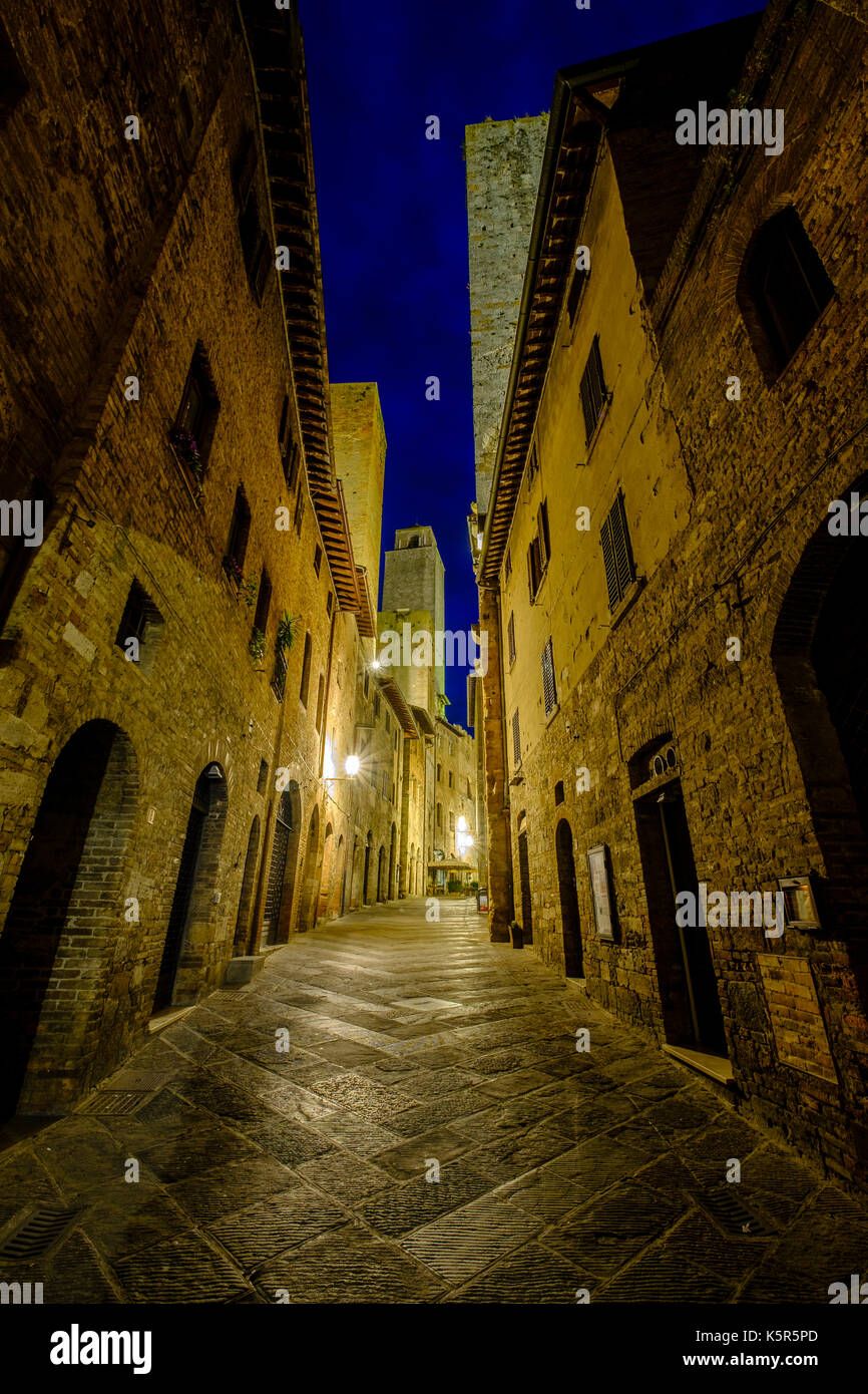 Alte Häuser und eine kleine Straße der mittelalterlichen Stadt, nachts beleuchtet Stockfoto