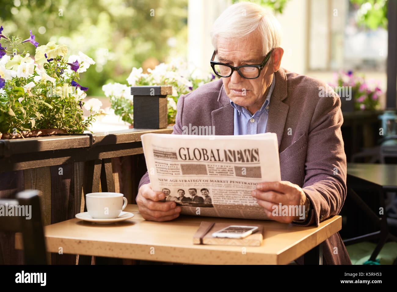 Portrait von älteren Mann lesen Zeitung beim Frühstück im Cafe im Freien Stockfoto