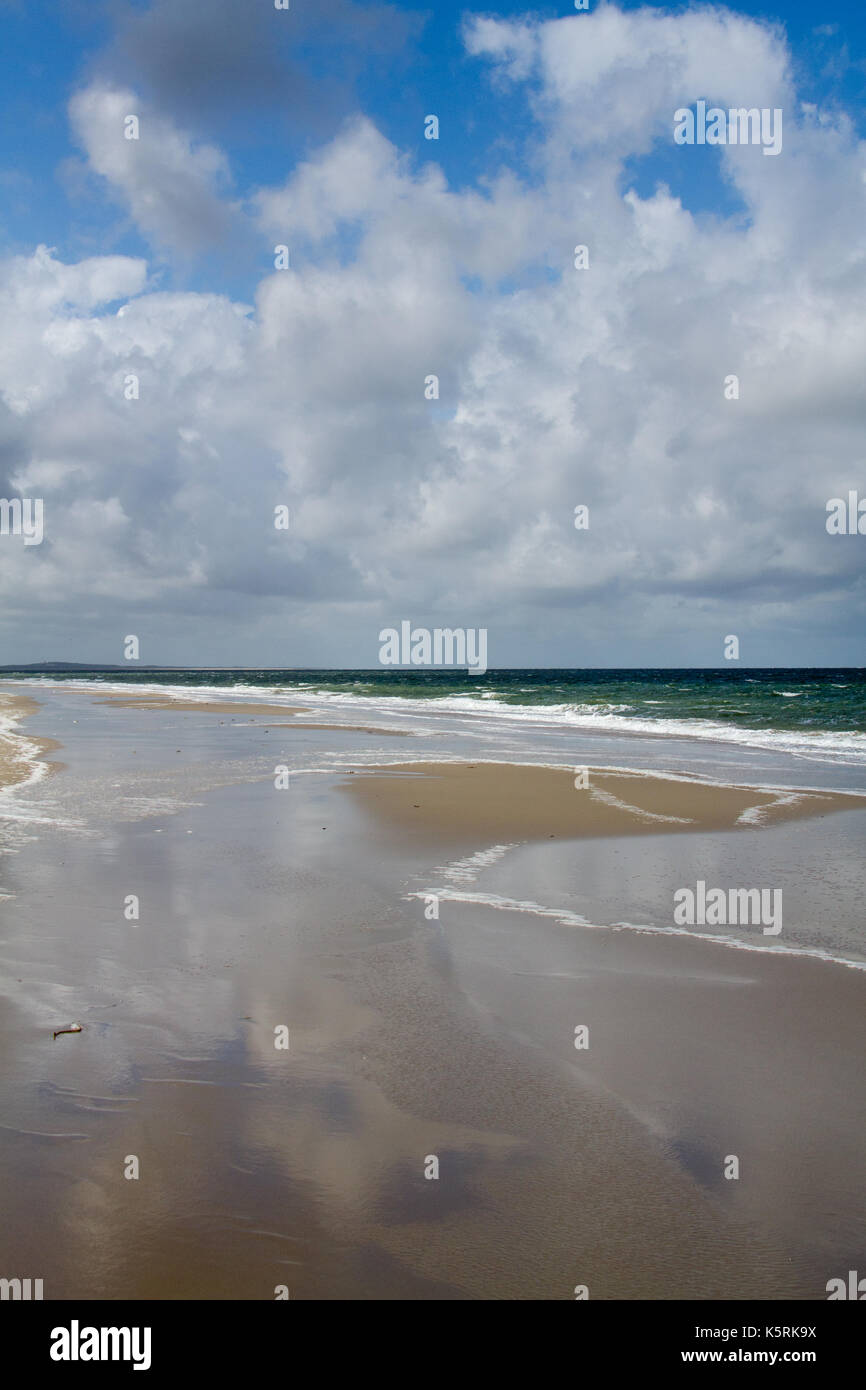 Das Meer bei Ebbe, blauer Himmel und Wolken im Wasser, am Strand links reflektiert. Stockfoto