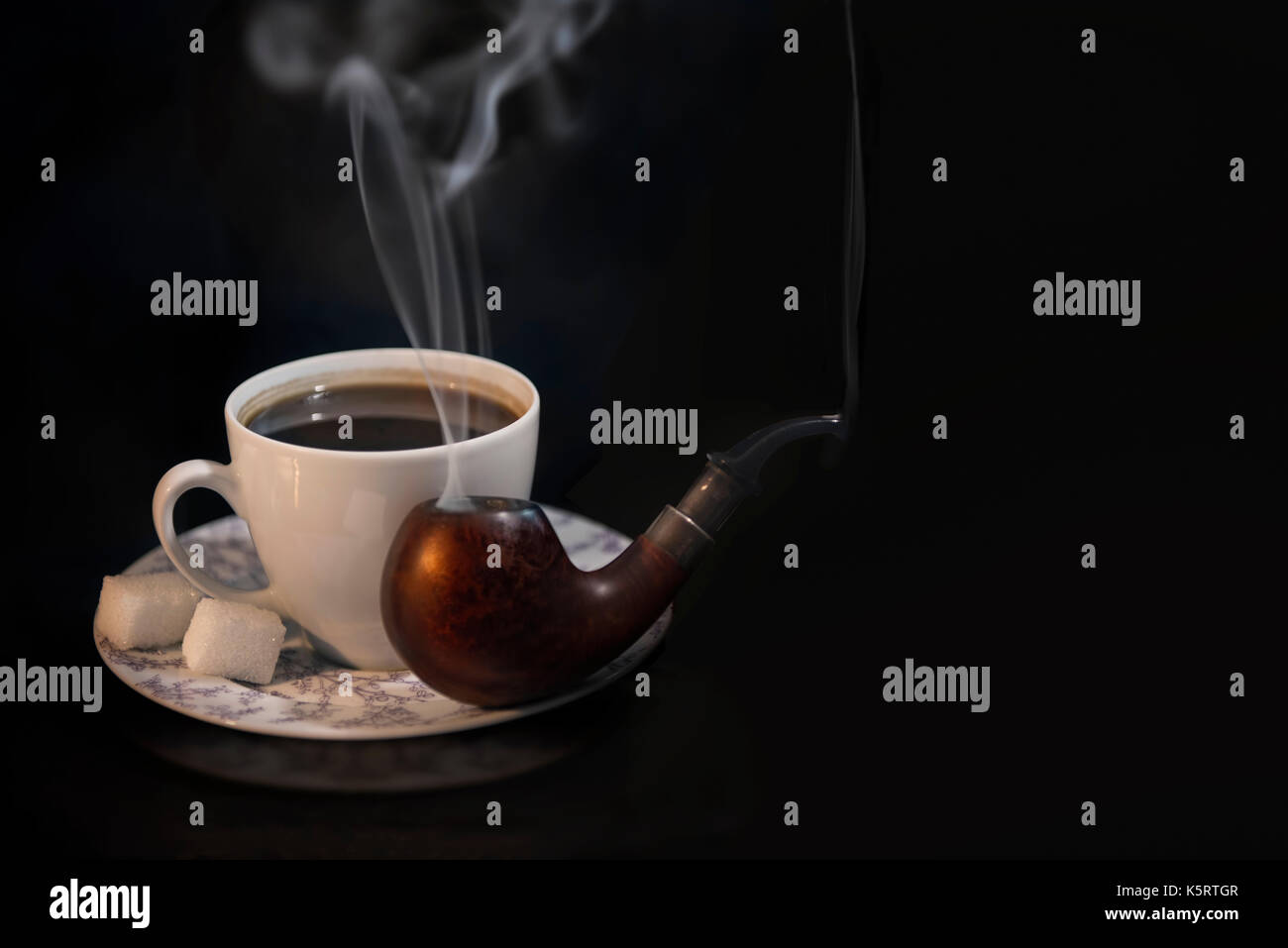 Ein schöner schwarzer Kaffee in weisser Tasse mit Zucker und eine rauchen Rohr auf einem schwarzen Hintergrund. Ein wunderbares Set für einen guten Abend rest Stockfoto