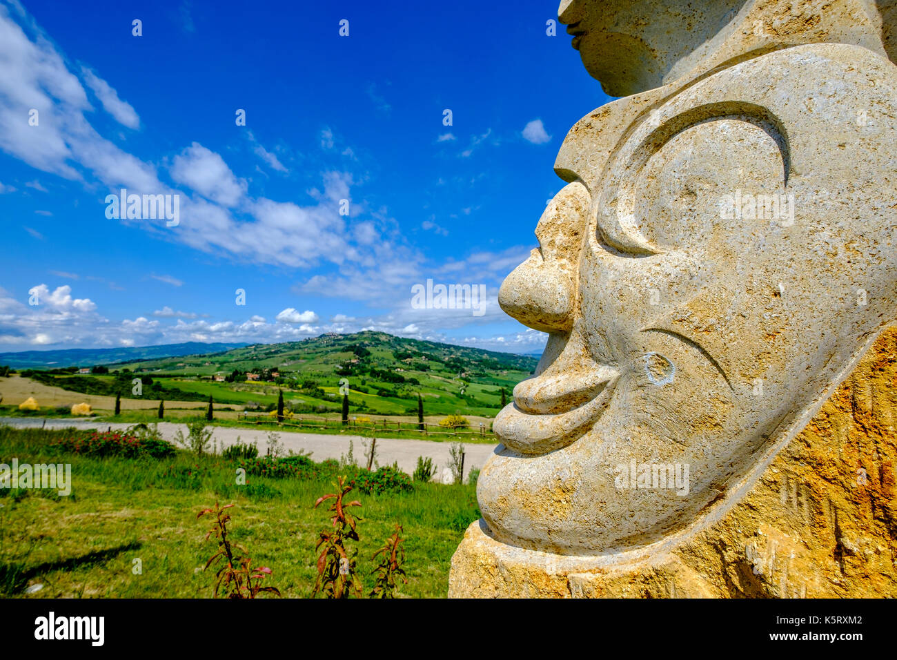 Typische tuscanian Landschaft mit Hügeln, Feldern, Zypressen und eine kunstvolle Fels gehauene Skulptur Stockfoto