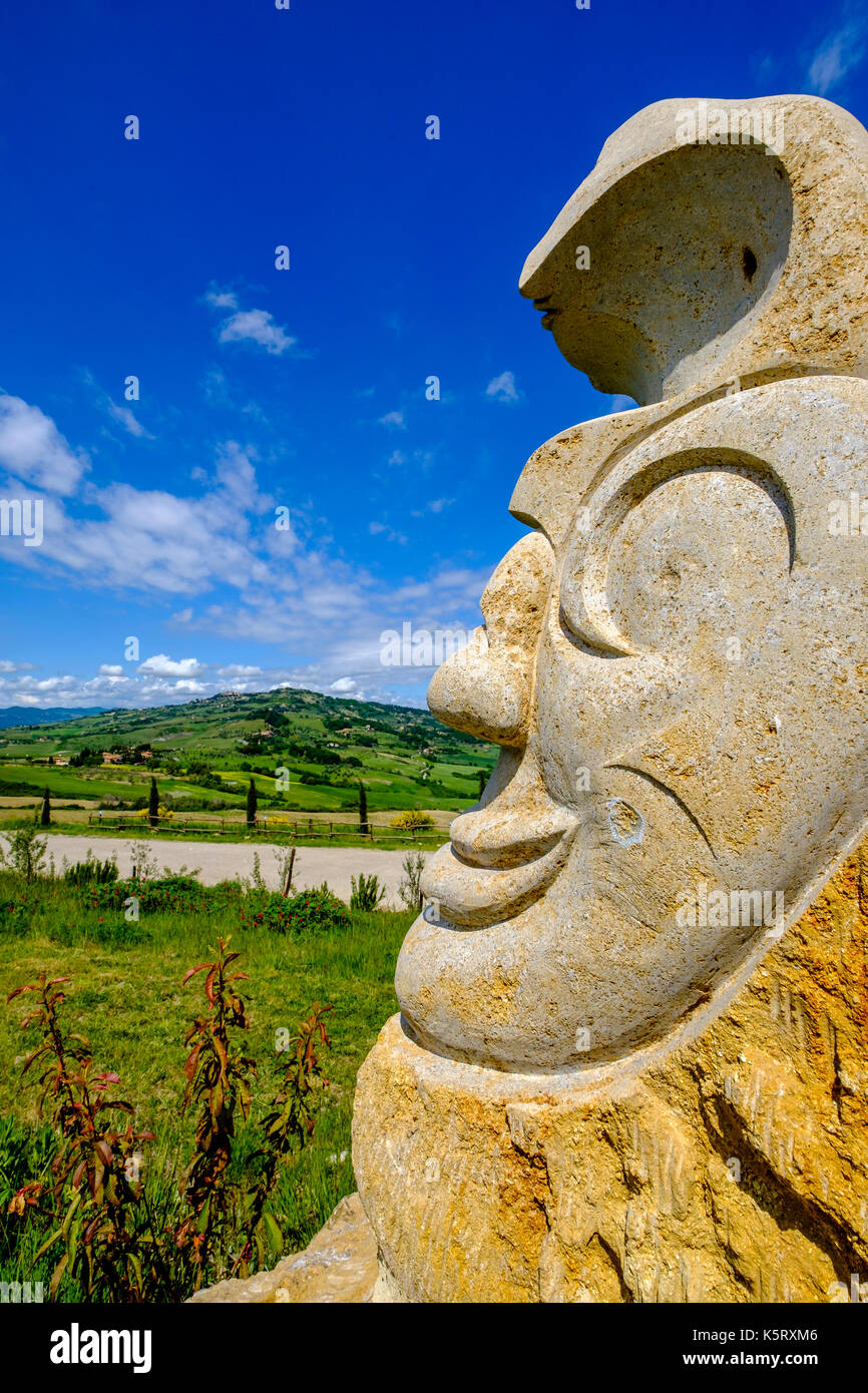 Typische tuscanian Landschaft mit Hügeln, Feldern, Zypressen und eine kunstvolle Fels gehauene Skulptur Stockfoto