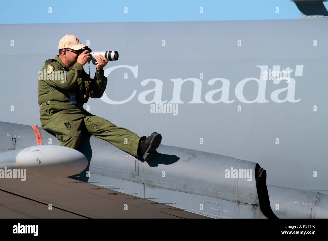 Crew Mitglied der Royal Canadian Air Force CP-140 Aurora saß auf dem Flügel seines Flugzeuges mit einer Kamera und das Fotografieren bei einer Flugschau Stockfoto
