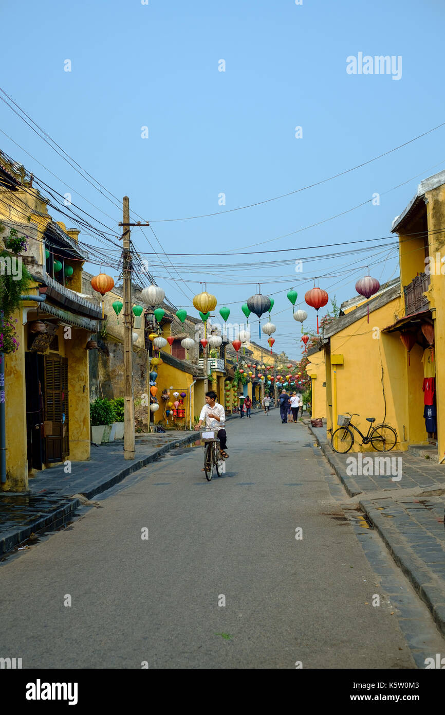 Radfahrer unter rote Laternen über eine Straße in Hoi-An, Vietnam Stockfoto