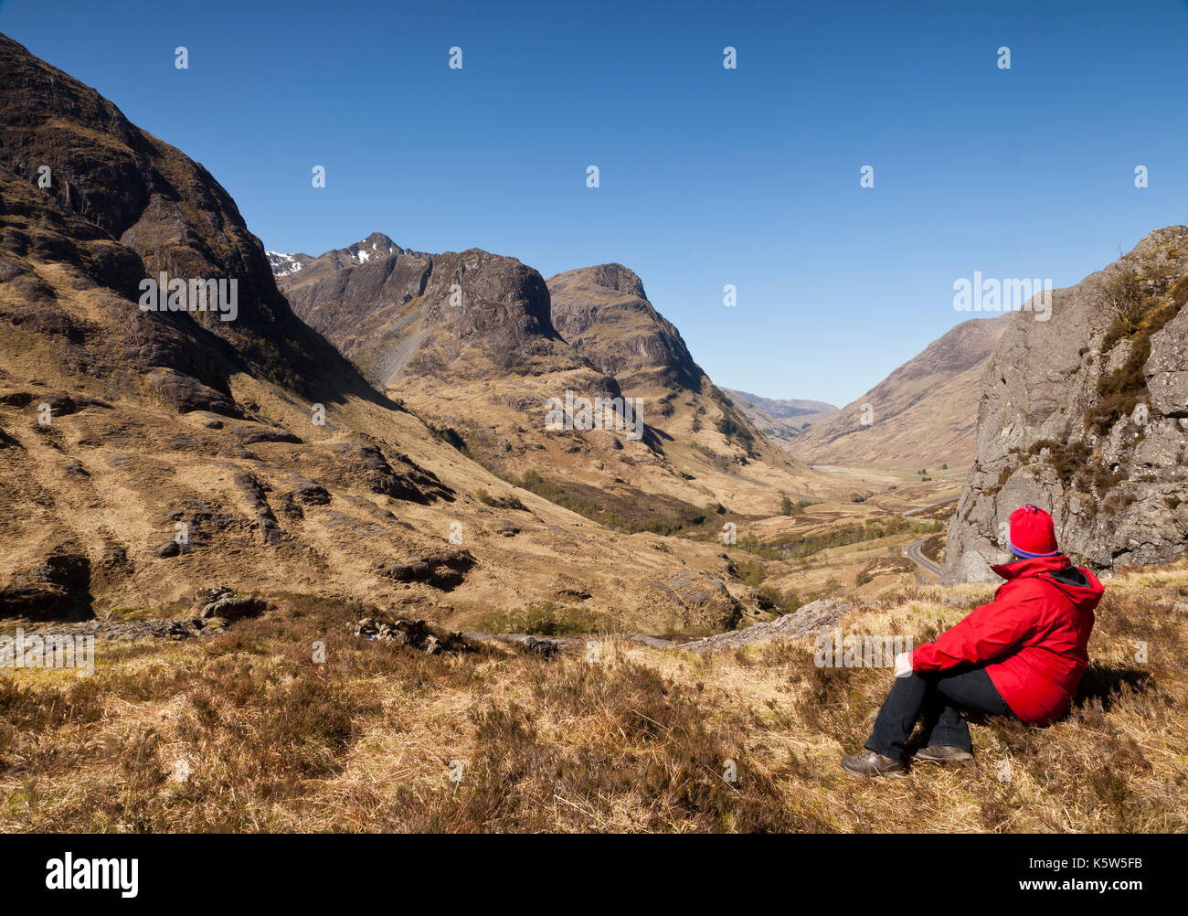 Eine Frau sitzt mit Blick auf die Studie, die Drei Schwestern von Glencoe, Schottland, UK Stockfoto