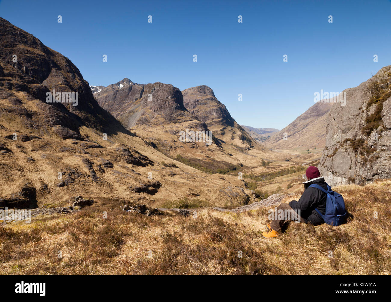 Ein Mann sitzt mit Blick auf die Studie, die Drei Schwestern von Glencoe, Schottland, UK Stockfoto