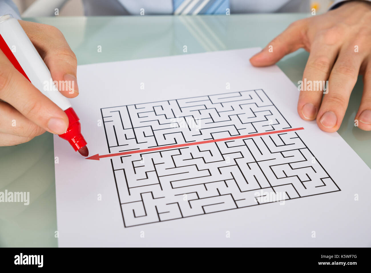 Nahaufnahme einer Person Hand Zeichnen von Geraden rote Linie über Labyrinth mit roter Markierung Stockfoto