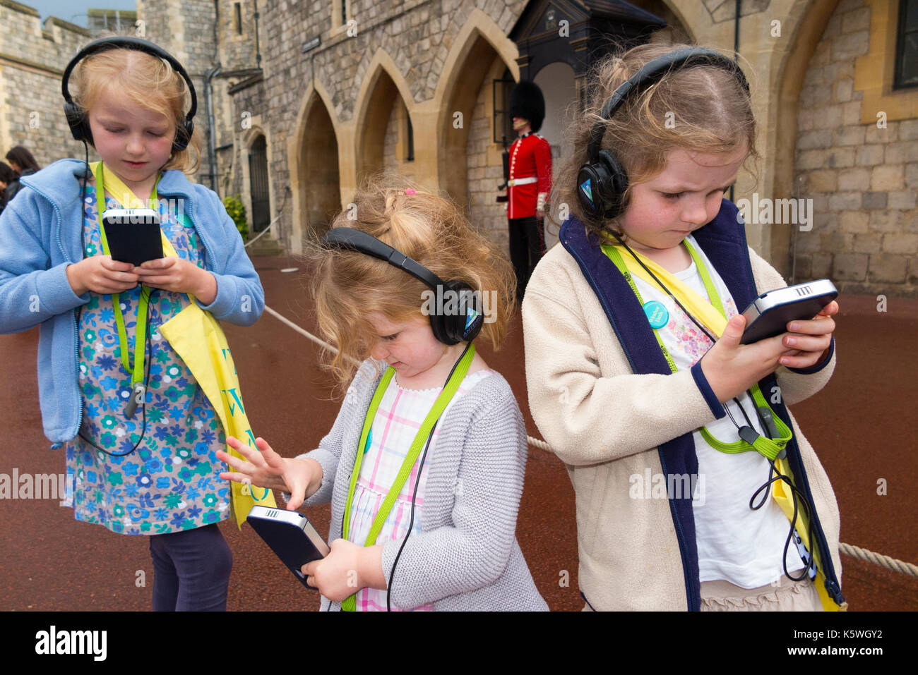 Drei Schwestern / Kinder / Kind / Kinder im Urlaub hören Sie einen Audio Guide Informationen während einer Tour in den Mauern von Schloss Windsor, Berkshire GROSSBRITANNIEN. Stockfoto
