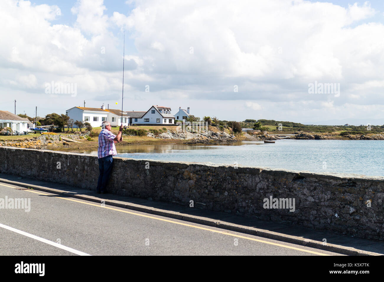 Mann angeln vom Road Bridge, Anglesey, Wales, Vereinigtes Königreich, Großbritannien Stockfoto