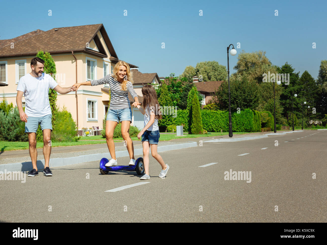 Liebevolle Familie Unterstützung Frau reiten Hoverboard Stockfoto