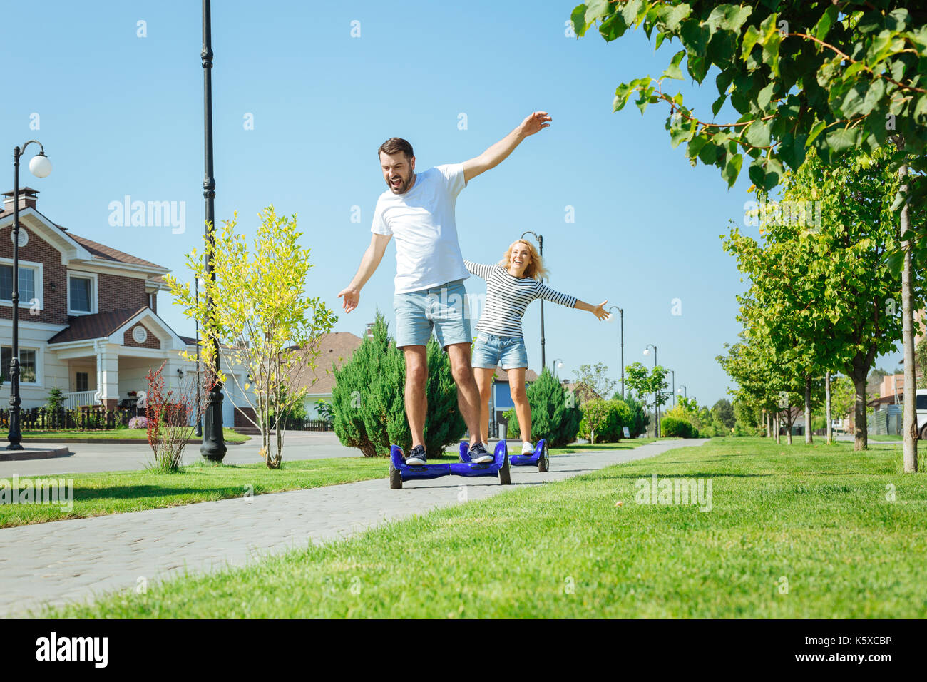 Fröhlicher Mann und seine Frau genießen hoverboard Fahrt Stockfoto