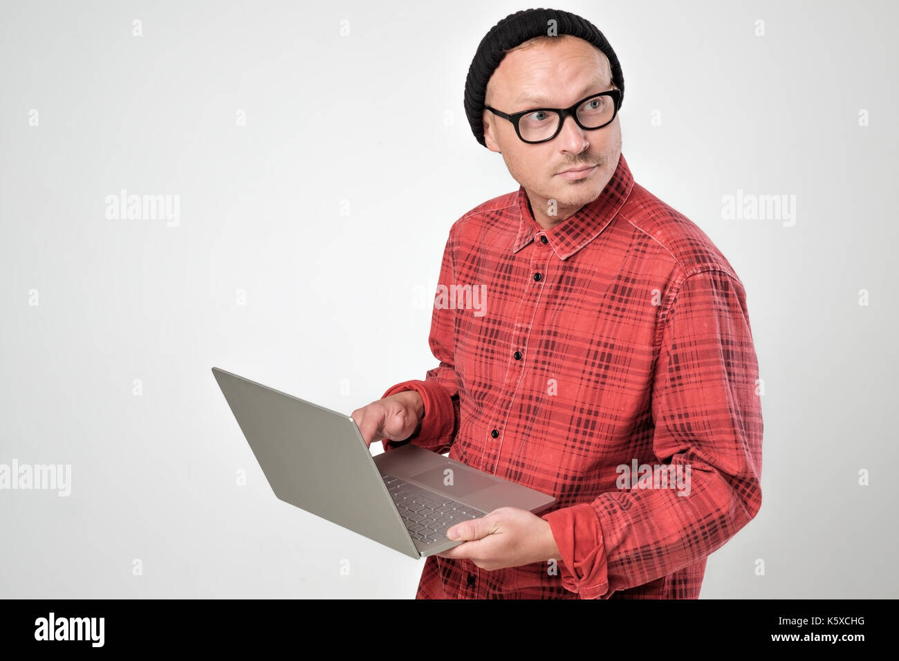 Kaukasische Mann mit mittels Fernbedienung und beiseite Suche Laptop. Stockfoto