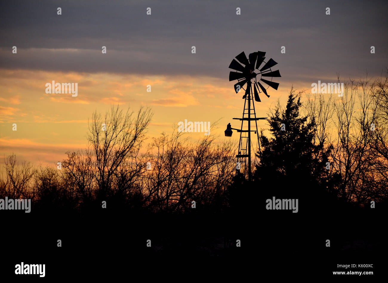 Alte Windmühle in Silhouette gegen einen Oklahoma Himmel bei Sonnenuntergang. Stockfoto