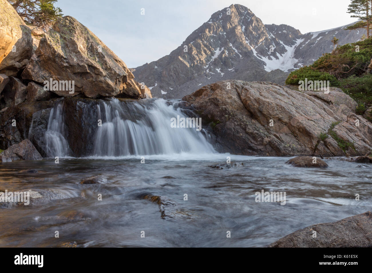 Ein Wasserfall mit dem Berg des heiligen Kreuzes in der Abstand in der heiligen Wüste, Colorado, USA. Stockfoto