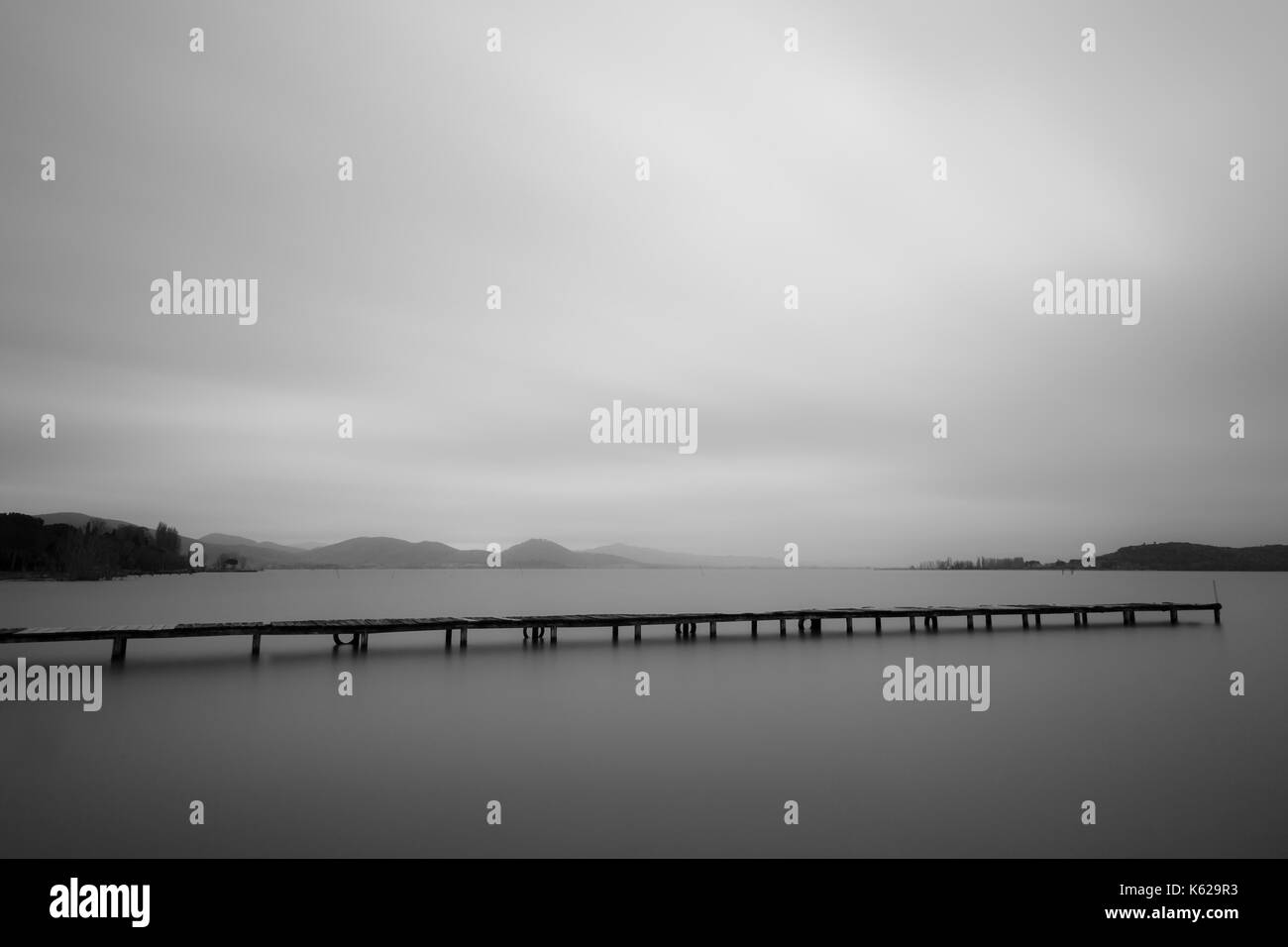 Minimalistische Ansicht eines langen Pier an einem See, mit perfekt noch Wasser und viel leerer Raum Stockfoto