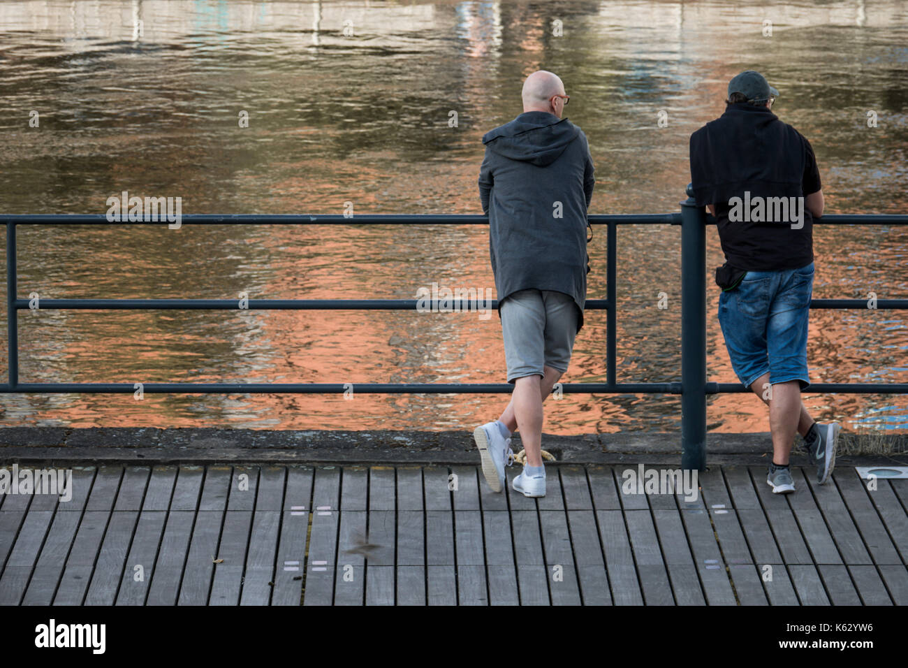 Bydgoszcz, Polen - August 2017: Zwei Männer stehen auf einer Blechbarriere ausgeruht und mit einem langsam fließenden Fluss Brda Stockfoto