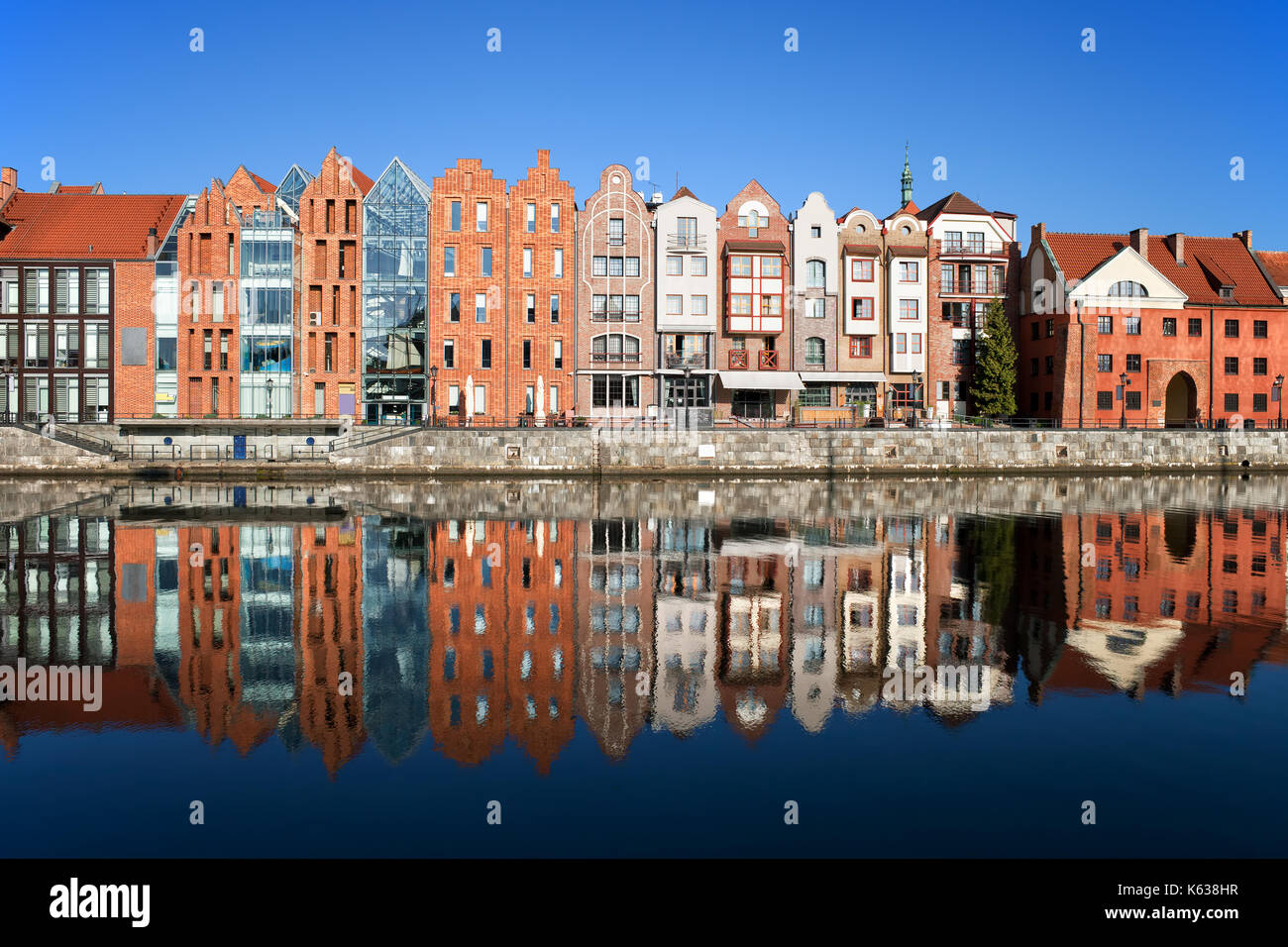 Stadt Danzig, Polen, Reihe von schmalen Häuser am Ufer des Flusses mit Spiegel Spiegelbild im Wasser. Stockfoto