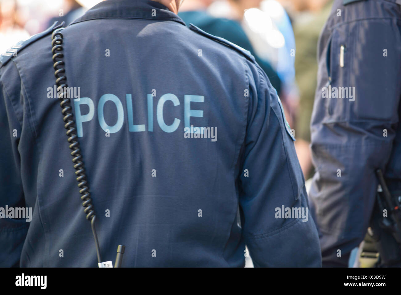 Ein Bild von der Rückseite eines uniformierten Polizisten im Dienst trägt blaue Overalls Stockfoto