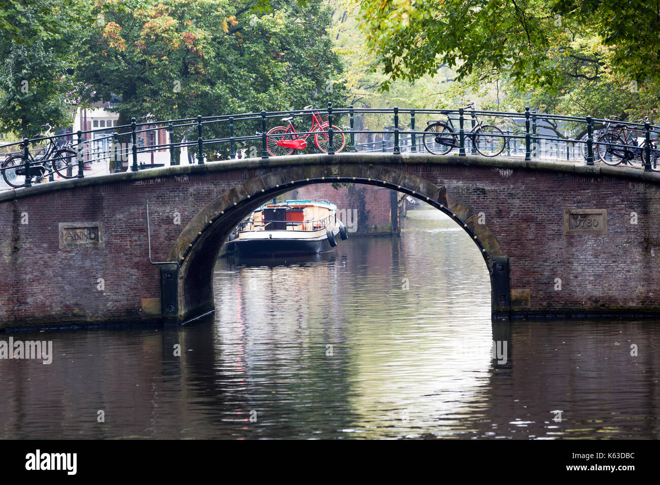 Kanal und ein rotes Fahrrad auf einer Brücke in Amsterdam geparkt Stockfoto