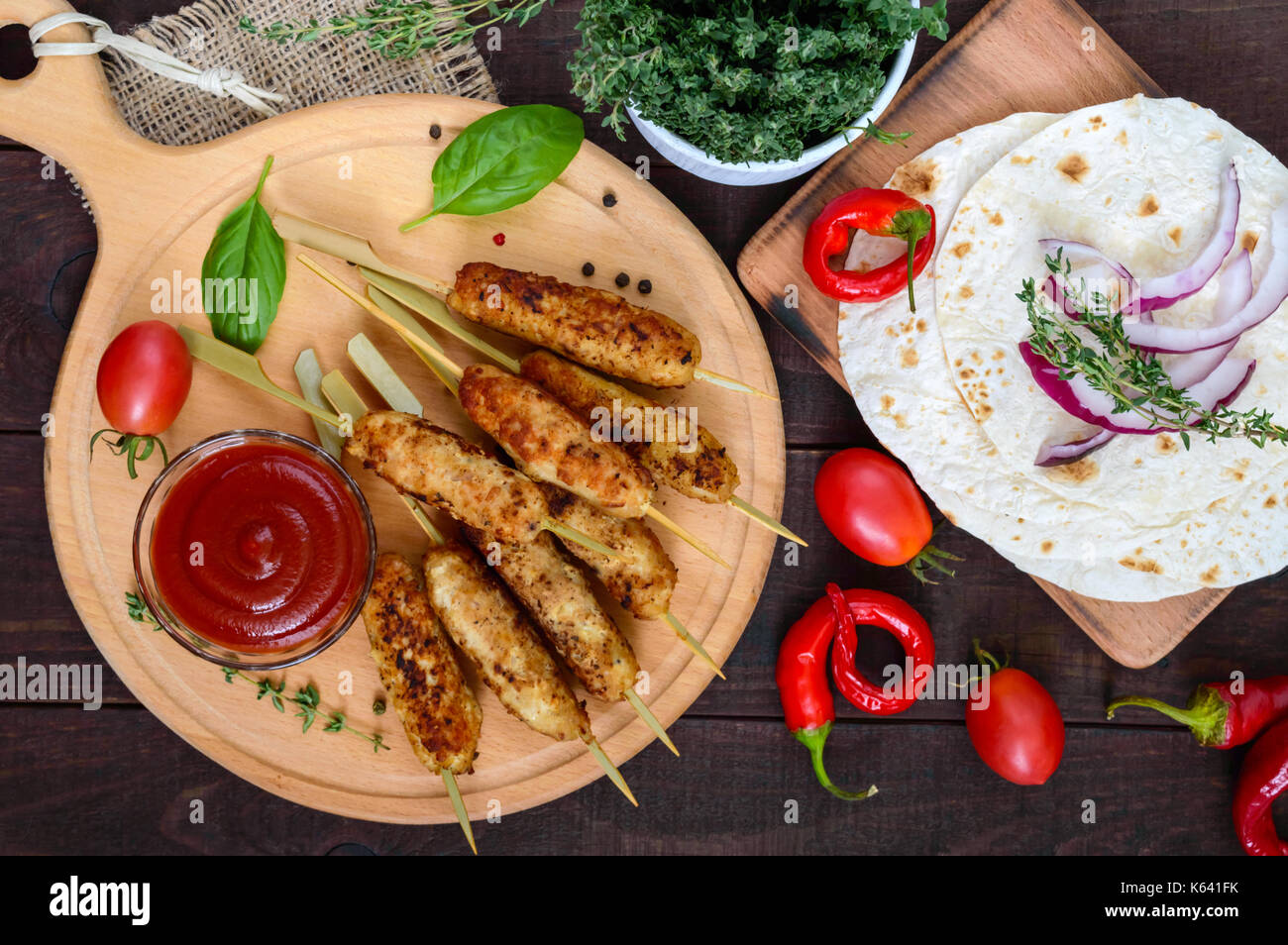 Lula Kebab ist ein traditionelles kaukasisches Gericht. Gehacktes Fleisch mit Spiessen. Mit Lavasch, Tomatensauce auf einem Holzbrett auf dunklem Grund servieren. Stockfoto