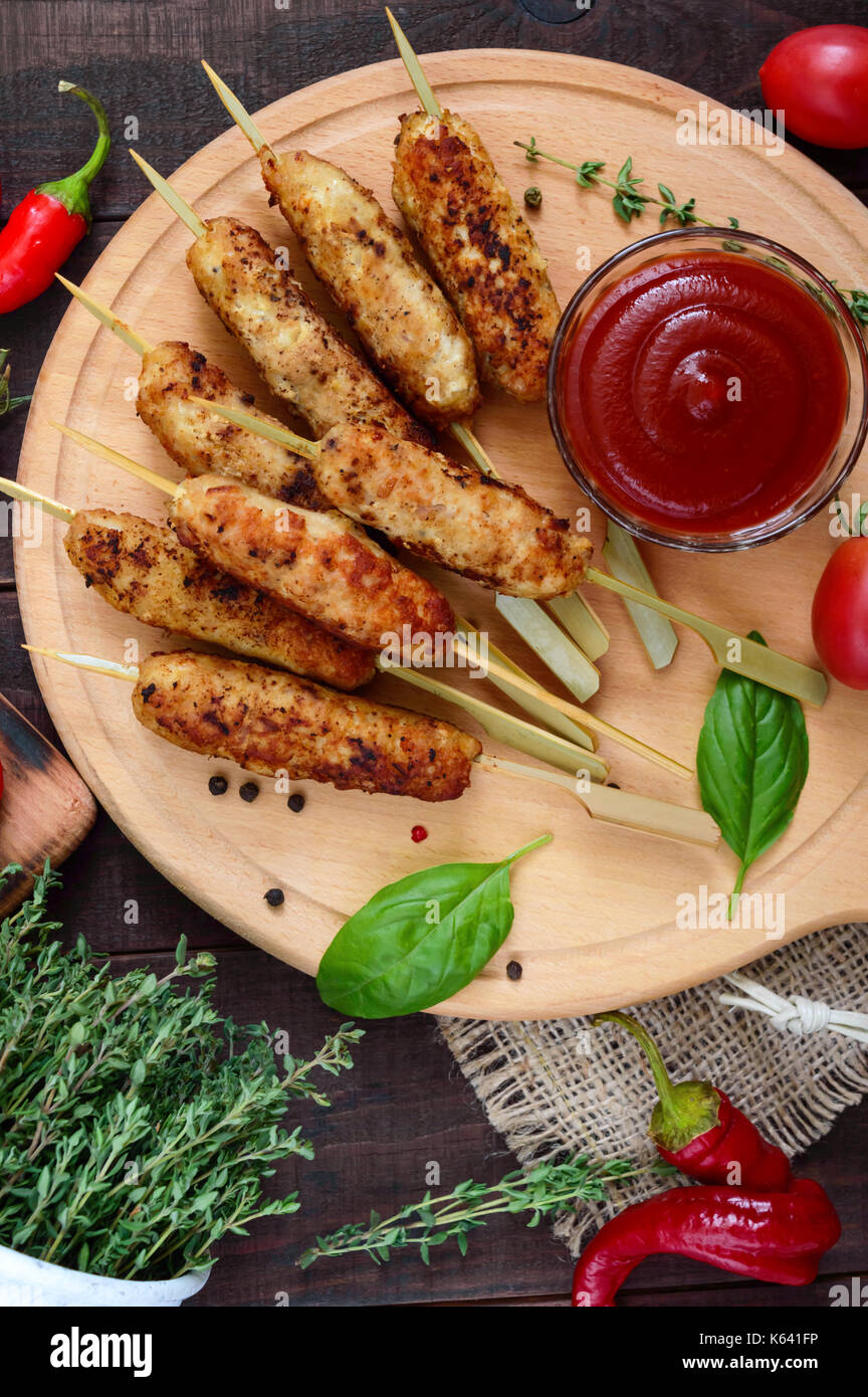 Lula Kebab ist ein traditionelles kaukasisches Gericht. Gehacktes Fleisch mit Spiessen. Mit Lavasch, Tomatensauce auf einem Holzbrett auf dunklem Grund servieren. Stockfoto