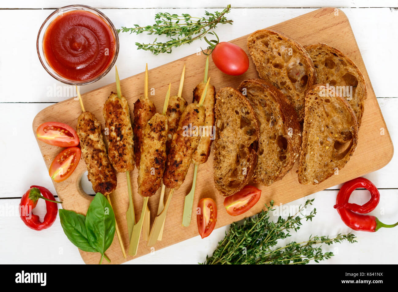 Lula Kebab ist ein traditionelles asiatisches Gericht. Gehackte gebratenes Fleisch am Spieß. Dienen auf einem Brett mit Müsli Ciabatta, Tomaten. Ansicht von oben. Stockfoto