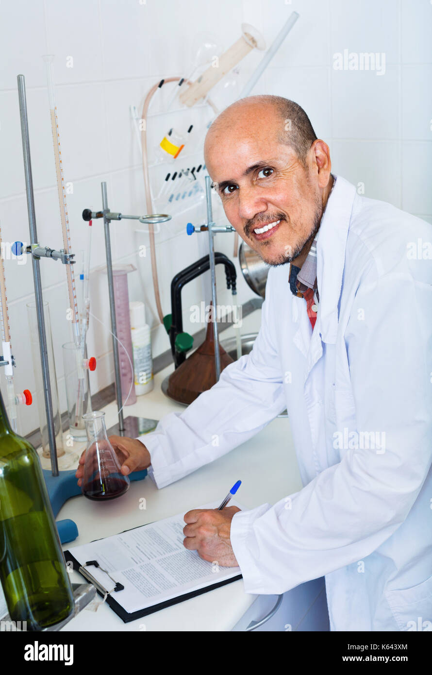 Aufmerksame fleißig lächelnd reifer Mann arbeiten im Hinblick auf die Qualität der Produkte im Weingut lab Stockfoto