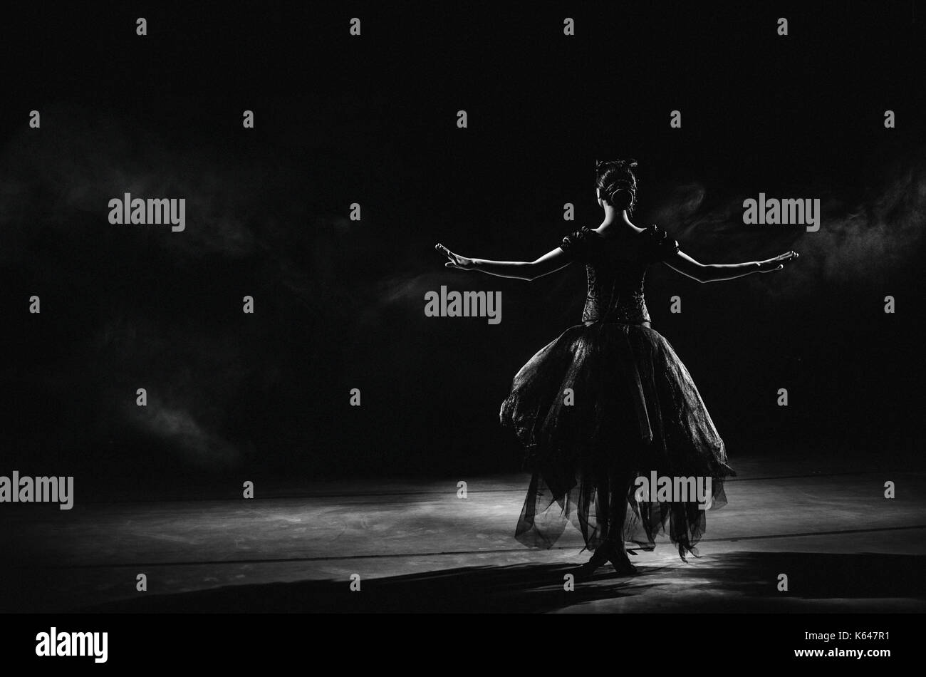 Licht Silhouette der elegante junge Ballerina stehend Zurück zur Kamera in der zweiten Position arme Pose auf dem schwarzen Hintergrund Stockfoto
