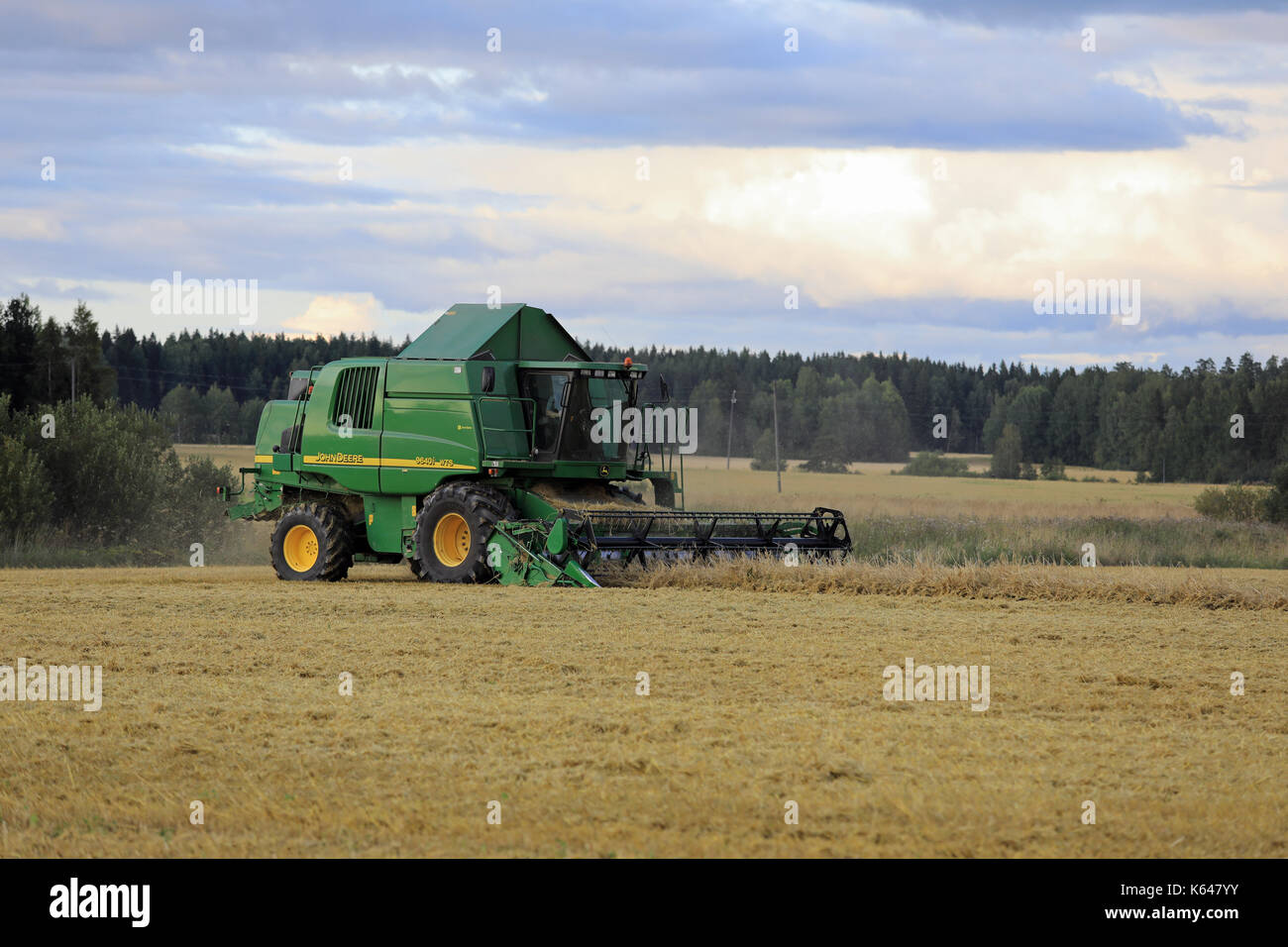 SALO, Finnland - 25. AUGUST 2017: Bauern ernten Getreide mit John Deere Mähdrescher 9460 habe ich an einem Herbstabend im ländlichen Süden Finnlands. Stockfoto